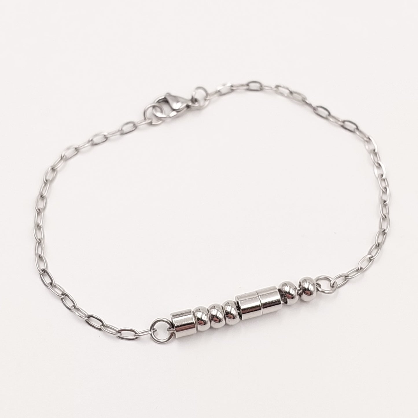 A silver chain bracelet with a morse code message in stainless steel beads clasp and a lobster clasp, displayed on a clean off-white background.