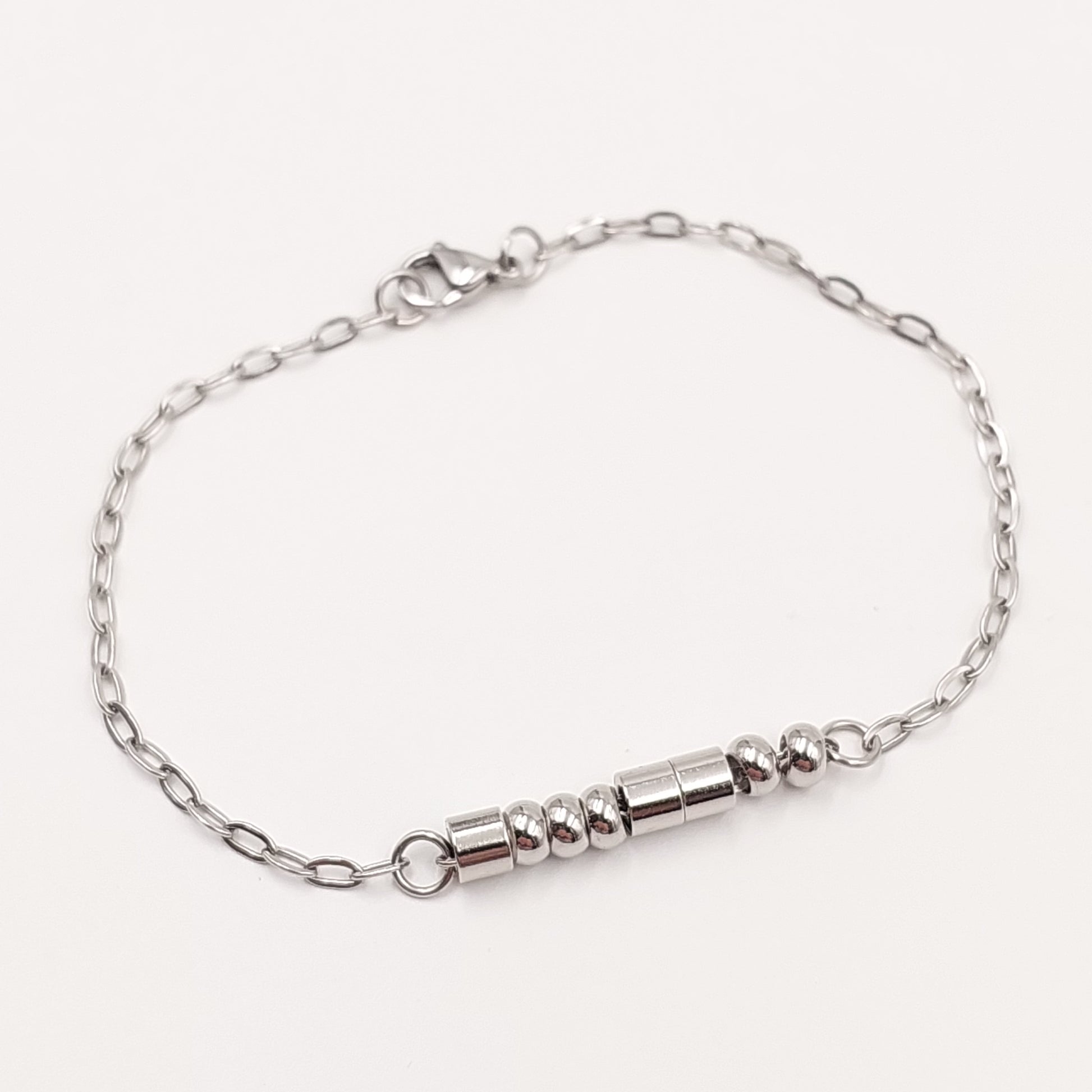 A silver chain bracelet with a morse code message in stainless steel beads clasp and a lobster clasp, displayed on a clean off-white background.